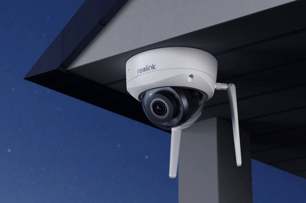 Zewnętrzna kamera monitoringu Reolink z wystającymi antenami, zamontowana pod dachem budynku.